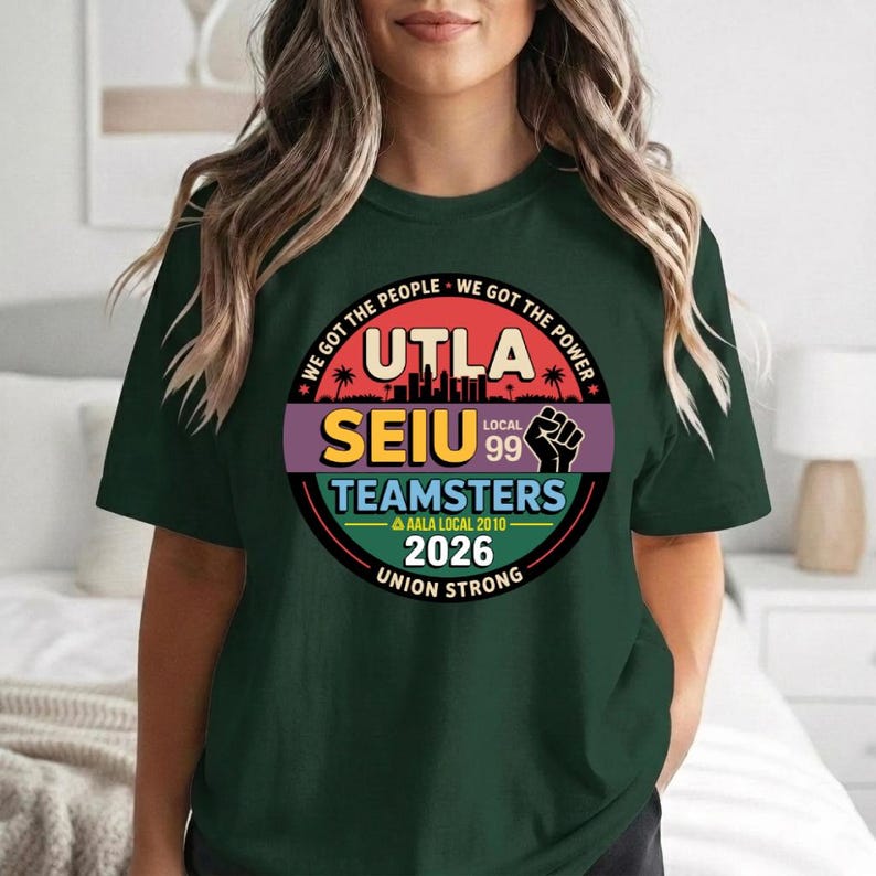 May include: Dark green t-shirt with a circular graphic featuring the text "UTLA SEIU Teamsters Local 99" and the phrases "We Got The People, We Got The Power" in red. The graphic also includes a fist and the year 2026.