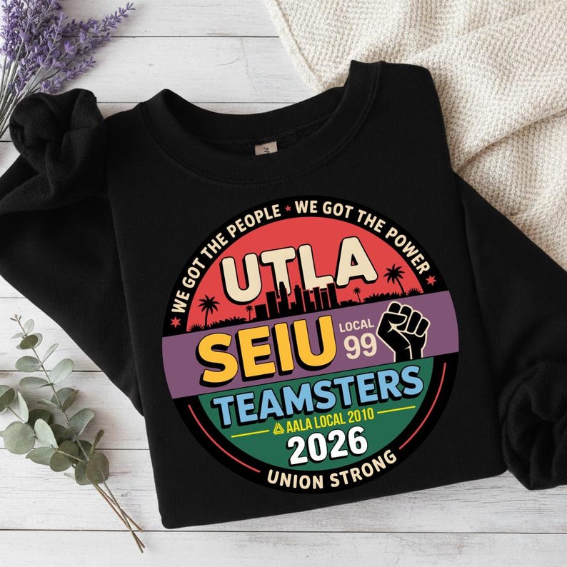 May include: Black crewneck sweatshirt with a circular graphic. The graphic features the text "UTLA SEIU TEAMSTERS LOCAL 99" with the words "WE GOT THE PEOPLE WE GOT THE POWER" around the top. The graphic also includes the text "AALA LOCAL 2010 2026 UNION STRONG".