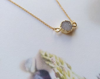 May include: A delicate gold chain necklace with a small, round, white agate pendant.