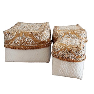 Könnte beinhalten: Drei geflochtene Körbe mit weißen bemalten Designs. Die Körbe sind aus natürlichen Materialien gefertigt und haben eine hellbraune Farbe. Der größte Korb befindet sich hinten, der kleinste vorne.