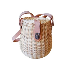 May include: A woven wicker handbag with a rounded shape and a light tan color. The bag features a light pink leather strap and a matching leather flap with a silver clasp. The bag has a top handle and a shoulder strap.