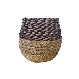 May include: A woven basket with a natural brown base and a black top. The basket is made of natural materials and has a round shape.