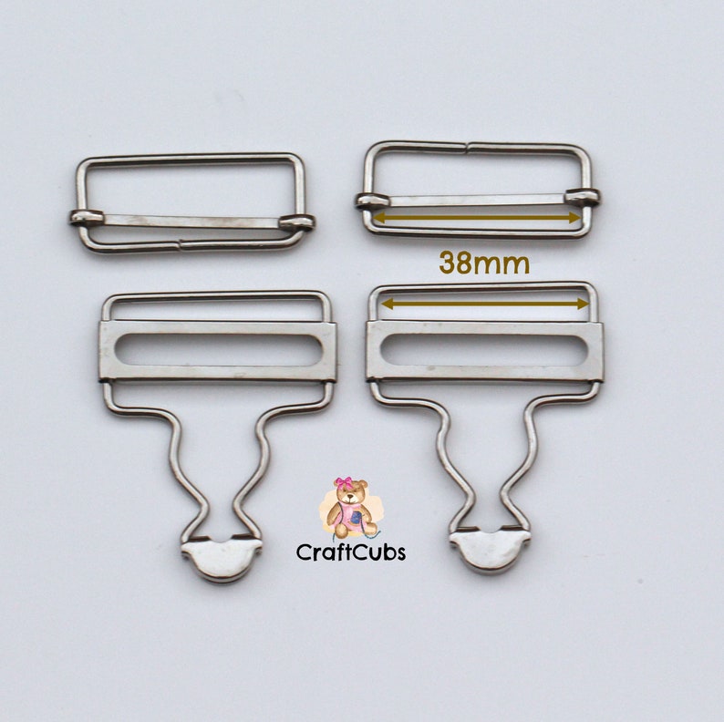 May include: Two silver metal garment clasps, one with a hook and one without. The clasp with the hook is 38mm wide.