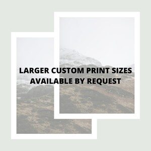 May include: A photograph of a mountain range with a white, snowy peak. The image is framed with a white border and the text "LARGER CUSTOM PRINT SIZES AVAILABLE BY REQUEST" is superimposed on the image.