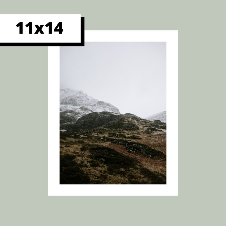 May include: A photograph of a snow-capped mountain range with a cloudy sky. The mountain range is covered in green vegetation and has a rocky, rugged texture.