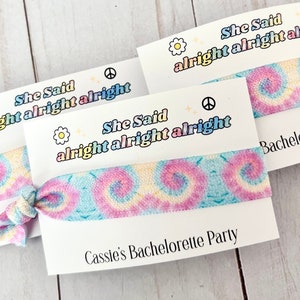 May include: Two tie-dye hair scrunchies with a white card that says "She Said alright alright alright" and "Cassie's Bachelorette Party".
