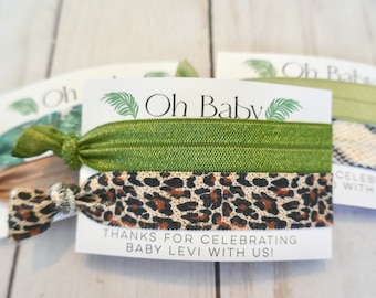 May include: Three green, brown, and beige hair ties with a card that says "Oh Baby" and "Thanks for celebrating Baby Levi with us!"