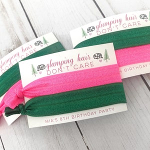 May include: Two green and pink hair ties with a white card that says "glamping hair don't care" and "MIA'S 8TH BIRTHDAY PARTY".