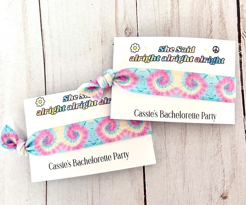 May include: Two tie-dye fabric wristbands with a white card attached to each. The card says "She Said alright alright alright" and "Cassie's Bachelorette Party".