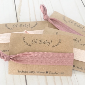 K&ouml;nnte beinhalten: Ein Set aus vier braunen Karten-Geschenken mit rosafarbenen Gummib&auml;ndern f&uuml;r Haare. Jede Karte tr&auml;gt den Text "Oh Baby!" und das Datum "5. Dezember 2020". Eine Karte tr&auml;gt au&szlig;erdem den Text "Sophia's Baby Shower".