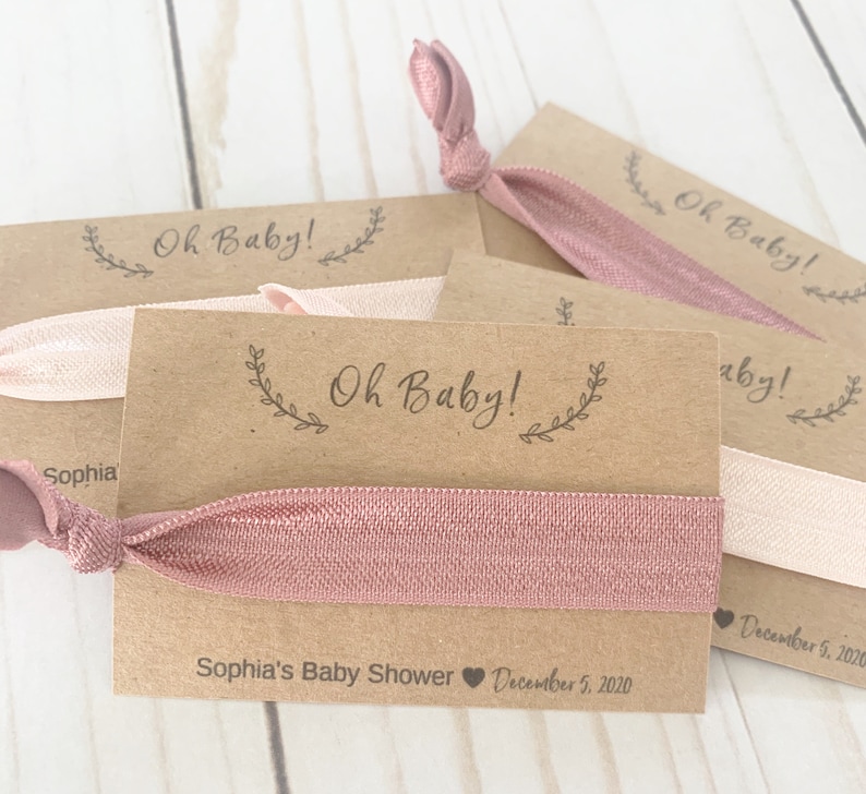 K&ouml;nnte beinhalten: Ein Set aus vier braunen Karten-Geschenken mit rosafarbenen Gummib&auml;ndern f&uuml;r Haare. Jede Karte tr&auml;gt den Text "Oh Baby!" und das Datum "5. Dezember 2020". Eine Karte tr&auml;gt au&szlig;erdem den Text "Sophia's Baby Shower".