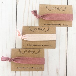 K&ouml;nnte beinhalten: Drei braune Karten mit dem Text "Oh Baby!" und einem rosafarbenen Gummiband, das an jeder Karte befestigt ist. Die Karten enthalten auch den Text "Sophia's Baby Shower" und das Datum "December 5, 2020".