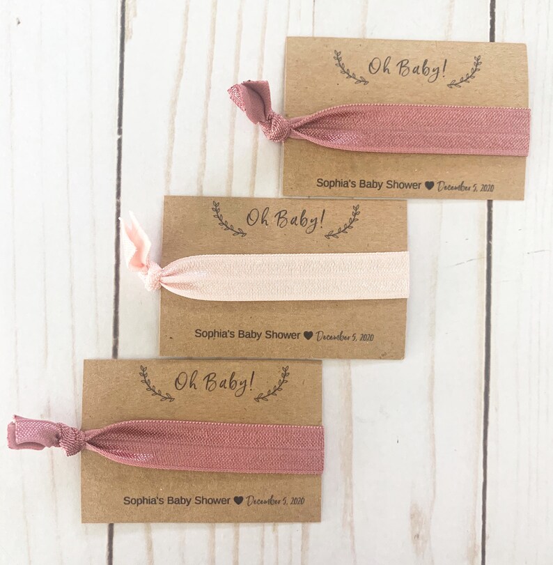 K&ouml;nnte beinhalten: Drei braune Karten mit dem Text "Oh Baby!" und einem rosafarbenen Gummiband, das an jeder Karte befestigt ist. Die Karten enthalten auch den Text "Sophia's Baby Shower" und das Datum "December 5, 2020".
