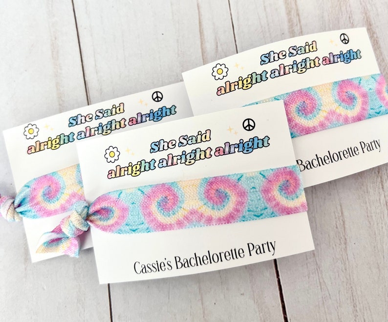 May include: Two tie-dye hair scrunchies with a white card that says "She Said alright alright alright" and "Cassie's Bachelorette Party".