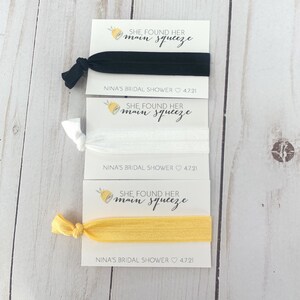 May include: Three hair ties with cards that say "She found her main squeeze" and "Nina's Bridal Shower 4.7.21". The hair ties are black, white, and yellow.