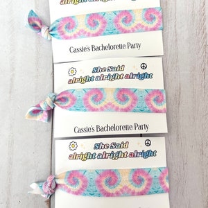 May include: Three tie-dye fabric hair scrunchies with the text "She Said alright alright alright" and "Cassie's Bachelorette Party" printed on white cards.