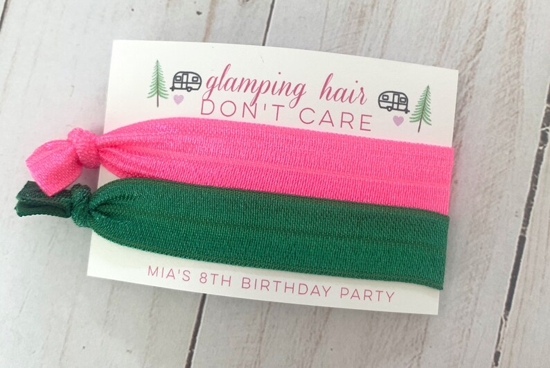May include: Two hair ties, one pink and one green, with a card that says "glamping hair don't care" and "Mia's 8th birthday party".
