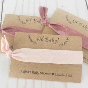 K&ouml;nnte beinhalten: Ein Set aus drei braunen Karten-Geschenken mit rosafarbenen Gummib&auml;ndern f&uuml;r Haare. Die Karten haben den Text "Oh Baby!" und "Sophia's Baby Shower December 5, 2020".
