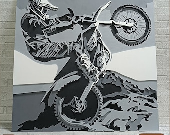 May include: A black and white illustration of a motocross rider performing a wheelie on a dirt bike. The rider is wearing a helmet and goggles. The bike has a large front wheel and a smaller rear wheel. The background is a gray and white gradient.