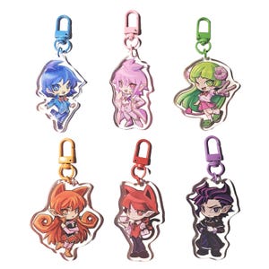 May include: Six acrylic keychains featuring anime-style characters with vibrant colors. Each keychain has a different character design, with various hair colors and outfits. The keychains have colored metal clasps for attachment.