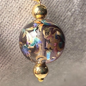 May include: A white ceramic mug with a black handle and the text "But First, Coffee" in a bold, black font. The mug is set against a blurred background. The mug appears to be approximately 10 cm tall.