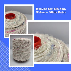 Peut inclure: Une bobine de fil de soie de sari recyclé de couleur blanc cassé avec des taches multicolores, dotée d'un noyau en plastique rouge. Le texte "Recycle Sari Silk Yarn (Prime) - White Patch" est imprimé en blanc sur un fond bleu au-dessus.