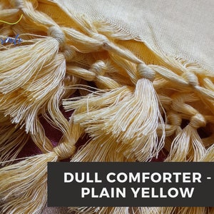 May include: A close-up of a yellow comforter with a fringe trim. The comforter is made of a soft, plush fabric and has a dull finish. The text "DULL COMFORTER - PLAIN YELLOW" is visible in the image.