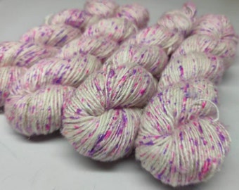 May include: White yarn with pink and purple speckles. The yarn is wound into a ball shape.