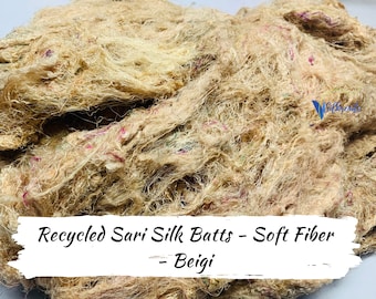 May include: A pile of beige recycled sari silk batts featuring soft, fibrous textures with small, colorful flecks of pink, green, and blue throughout. The image includes the text: Recycled Sari Silk Batts - Soft Fiber - Beigi.