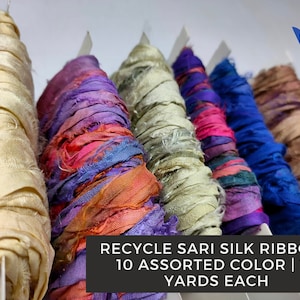 May include: A selection of colourful recycled sari silk ribbon in various shades. The image displays multiple spools of ribbon in cream, pink, purple, blue, and green. Text on the image reads "Recycle Sari Silk Ribbon - 10 Assorted Color | 10 Yards Each."