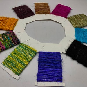 Puede incluir: Una rueda de colores de 10 carretes de hilo de diferentes colores. Los colores son marrón, morado, verde, azul, negro, amarillo, verde y amarillo, rosa y verde, azul y un carrete multicolor.