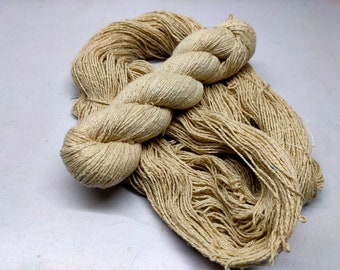 May include: A skein of natural beige yarn made from a natural fiber like cotton or linen. The yarn is loosely wound and ready for knitting or crocheting.