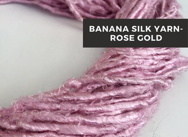Puede incluir: Primer plano de un suave hilo de seda de pl&aacute;tano de color rosa dorado. El hilo est&aacute; enrollado holgadamente en un c&iacute;rculo, mostrando su textura y brillo.
