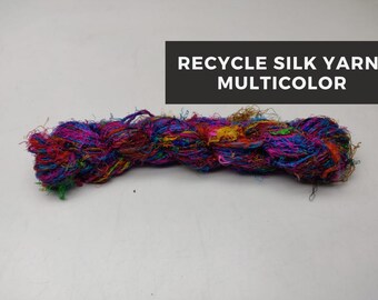 May include: A skein of colorful recycled silk yarn. The yarn is a mix of pink, blue, green, yellow, and brown.
