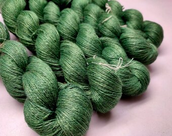 May include: A skein of green yarn, made of a soft, natural fiber. The yarn is tightly wound and has a subtle sheen.