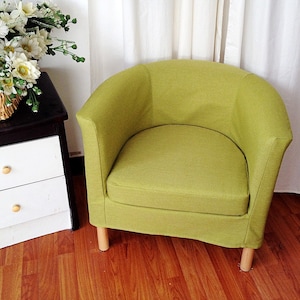 May include: A green upholstered armchair with wooden legs. The chair has a rounded back and a wide seat.