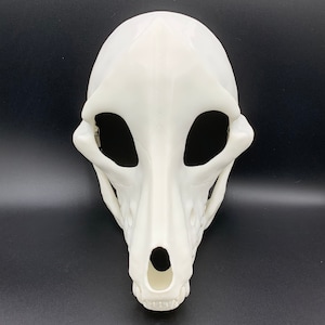 K&ouml;nnte beinhalten: Wei&szlig;e Plastikmaske eines Hundeskulls mit Augenl&ouml;chern und einem Nasenloch. Die Maske ist eine 3D-gedruckte Nachbildung eines Hundeskulls.