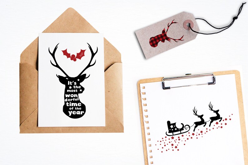 May include: A black and white silhouette of a reindeer with the text "It's the most wonderful time of the year" inside the silhouette. A red holly berry with green leaves is above the reindeer. The image is on a white card with a brown envelope.