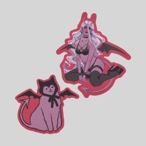 May include: Two pink and red devil character stickers. One is a female devil with white hair, wearing a black bra and a black choker. The other is a cat-like devil with black ears and a black bow tie.