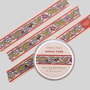 Puede incluir: Un rollo de cinta washi Faerie Folk con tres tiras de cinta desplegadas. La cinta presenta un patrón repetitivo de hojas de roble verdes, bellotas marrones y bayas rojas sobre un fondo crema. La etiqueta dice Faerie Folk, Washi Tape, Art by Elithien, 15 mm x 10 m.