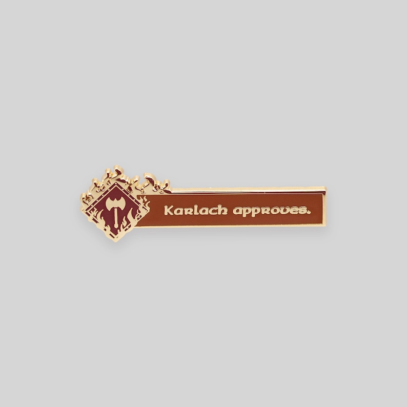 May include: Gold and red enamel pin with a stylized axe and flames, and the text "Karlach approves."