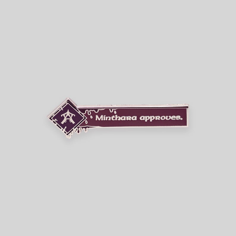 May include: A purple enamel pin with a dripping blood effect. The pin features a stylized symbol and the text "Minthara approves."