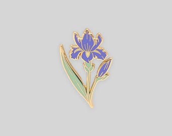 May include: A gold-toned metal enamel pin shaped like an iris flower. The design features a vibrant purple bloom with a pale yellow center, a light green stem and leaf, and a small purple bud, all outlined in polished gold metal lines.