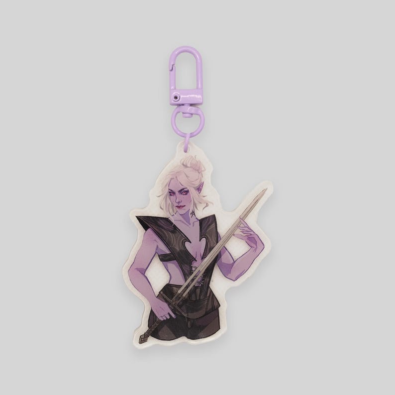 May include: Purple and white keychain featuring a character holding a sword. The character has purple skin, long white hair, and is wearing a black and silver outfit.