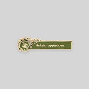 May include: Gold-colored enamel pin with a green background. The pin features a stylized tree branch with a bear paw print and the text "Halsin approves."