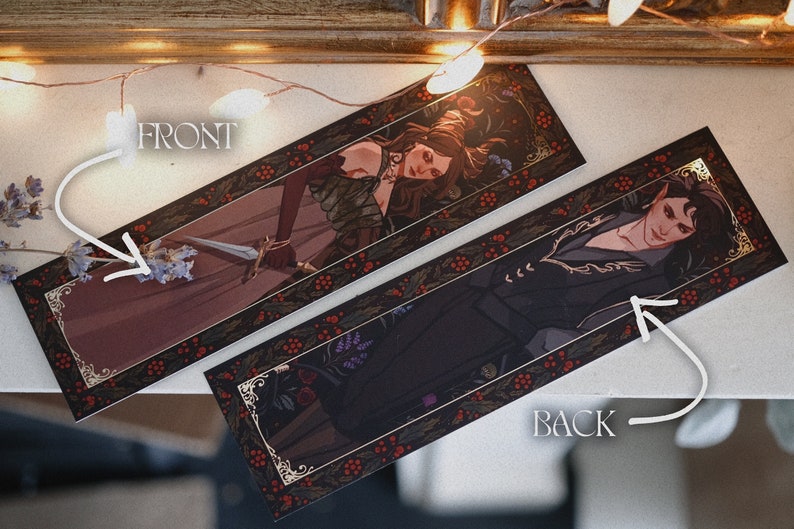 May include: Two bookmark designs with gold accents and a dark background. The front features a woman with long red hair holding a sword. The back features a person with dark hair wearing a black jacket. Both bookmarks have a red berry and leaf border.