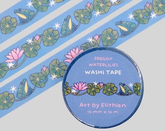 May include: A roll of light blue washi tape featuring a repeating pattern of green frogs, pink water lilies, and white star accents. The label reads FROGGY WATERLILIES WASHI TAPE, Art by Elithien, 15 mm x 10 m. The tape is shown unrolled in strips.