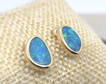 Puede incluir: Un par de pendientes de oro con piedras preciosas de ópalo azul de forma ovalada.