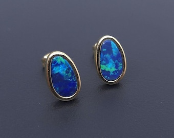 Puede incluir: Un par de pendientes de oro con piedras preciosas de ópalo azul de forma ovalada.
