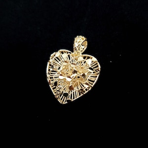 Può includere: Un ciondolo a forma di cuore in oro con un delicato design a filigrana. Il ciondolo è realizzato in metallo traforato intricato e ha una finitura lucida.